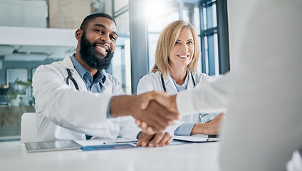 Image showing Handshake, partnership or happy doctors in a meeting after successful medical surgery or reaching healthcare goals. Teamwork, woman or black man smiles shaking hands with a worker in hospital office