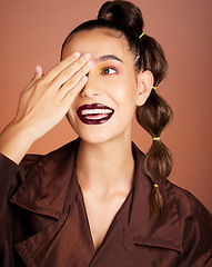 Image showing Woman, beauty makeup and smile in studio with edgy fashion, hair and face by cosmetic background. Model, cosmetics and facial art with creative hairstyle, aesthetic and hand on eye by studio backdrop