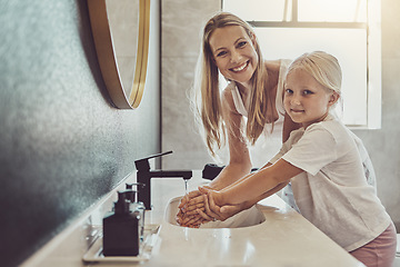 Image showing Bathroom, mother and child cleaning hands with water, soap or learning healthy hygiene in portrait together. Washing dirt, germs or bacteria on fingers, mom and girl in home with smile, help and care