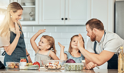 Image showing Family in kitchen, cooking together with high five and teaching kids, learning nutrition and happy parents. Mom, dad and girl children help making healthy food in home with care, success and lunch.