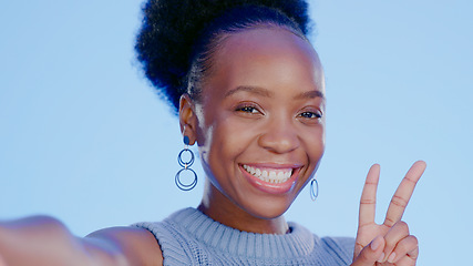 Image showing Happy, selfie and black woman with peace sign with smile isolated in a studio blue background as emoji. Happiness, cool or portrait of person with v hand gesture for social media picture online