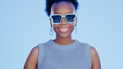 Image showing Portrait, sunglasses and smile, black woman in studio with cool, trendy summer fashion and creative mockup. Happiness, luxury eyewear and excited, fun model with designer frame on blue background.