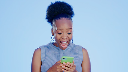 Image showing Shock, phone and black woman in a studio with good news on the internet for winning a bet. Happy, surprise and excited young African female model scroll on cellphone isolated by blue background.