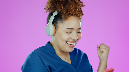 Image showing Woman, phone and happy fist with headphones for winner, promotion or announcement in studio on purple background. Smartphone, person and excited for notification, sale and lottery with mock up space