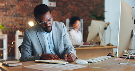 Image showing Black man, planning and writing notes in office with business agenda, administration or review of schedule. Businessman, notebook and report on computer research, information or management strategy