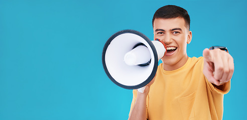 Image showing Megaphone, smile and portrait of man in studio pointing for announcement, speech or rally. Happy, protest and young person from Canada with bullhorn for loud communication isolated by blue background