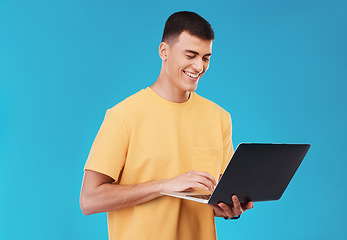 Image showing Laptop, research and man student in a studio working on a university project on the internet. Smile, technology and young male person studying for college test or exam on computer by blue background.