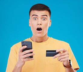 Image showing Credit card, ecommerce and man with a cellphone, surprise and transaction on a blue studio background. Person, shock and model with a smartphone, digital app and online banking with finance and fraud