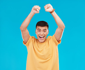 Image showing Man, winner and yes for student success, college news and celebration for winning, goals or achievement in studio. Happy portrait of young person in wow, excited and fist for power on blue background