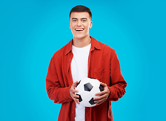 Image showing Soccer ball, happy and portrait of man on blue background for sports, winner and achievement. Smile, football fan and person cheer for team success, winning match, game and tournament in studio