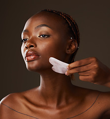 Image showing Woman, facial and gua sha in hand on studio background for mockup in beauty, treatment or skincare. Black person, model or massage for glow, lymphatic drainage or grooming with tool, relax and shine