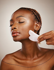 Image showing Woman, beauty and gua sha for face massage, aesthetic skincare and anti aging dermatology in studio on grey background. African model, crystal stone tools or lymphatic drainage with facial cosmetics