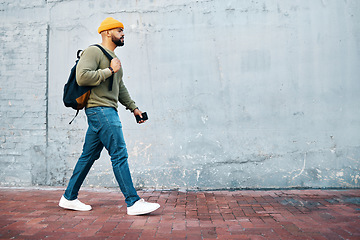 Image showing Student, walking and travel with man on wall, mockup and space in urban, campus or street in town. University, person and commute on path, road or journey to college in city with phone or backpack