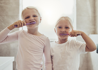 Image showing Children, brushing teeth and a girl with her sister in the bathroom of their home together for oral hygiene. Portrait, dental cleaning and siblings using a toothbrush in the morning for mouth care
