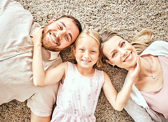 Image showing Happy, portrait and child with parents in the living room bonding and relaxing together at home. Happiness, love and girl kid laying with mother and father from Australia on floor in lounge at house.