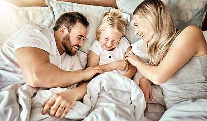 Image showing Bed, top view and happy family bond with tickle, games and laughing in their home together. Bedroom, fun and above parents with girl child in a house with care, support and love, security or playing