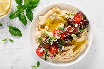 Image showing Greek style vegan mediterranean hummus with fresh vegetables, olives, olive oil and feta cheese. Top view