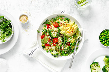 Image showing Couscous salad with broccoli, green peas, tomatoes, avocado and fresh arugula. Healthy natural plant based vegetarian food for lunch, israeli cuisine, top view