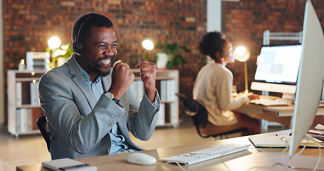 Image showing African man, call center and celebration by computer, smile and excited for promotion, goals or success. Consultant, winner or agent in night, telemarketing or customer service with fist in workplace
