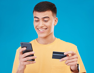 Image showing Credit card, ecommerce and man with a smartphone, payment and transaction on a blue background. Person, guy and happy model with a cellphone, digital app and online banking with finance and savings