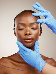 Image showing Portrait, gloves and plastic surgery on face of a black woman in studio on a gray background for cosmetic change. Patient, skincare transformation and a young model getting ready for facial treatment
