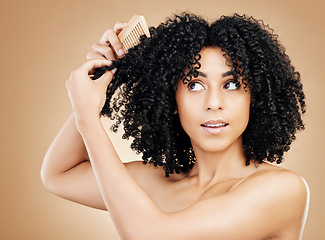 Image showing Afro, brush and hair of woman in studio for beauty, natural growth and grooming on brown background. Model comb curly hairstyle, coil texture and care for salon aesthetic, healthy treatment and shine