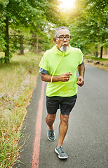 Image showing Senior man, running and road in nature, countryside or forest with exercise in retirement for cardio, health and wellness. Fitness, training and person breathing in workout, sport on run in woods