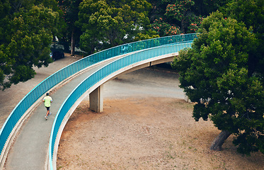 Image showing Above, man and running on bridge in nature, countryside or outdoor in environment with path in woods. Athlete, run or walking on road for cardio, fitness or exercise in forest with eco infrastructure