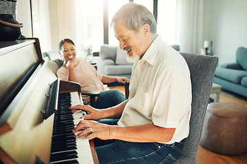 Image showing Senior man playing piano for music in living room with wife for bonding, entertainment or having fun. Happy, smile and elderly Asian couple in retirement enjoying keyboard instrument at modern home.