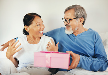 Image showing Senior, man and woman with gift in bedroom for anniversary, romantic or together. Asian, elderly couple and bond by smile in happiness for celebration by surprise expression on face, embrace and love