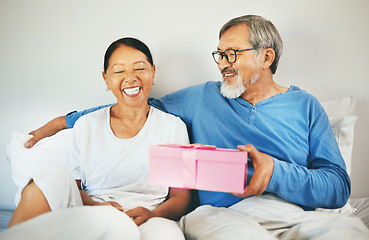 Image showing Happy couple in bed, senior or surprise gift for anniversary, care or love in home, house or retirement. Eyes closed, mature Asian man or excited woman with birthday present box for romance or smile