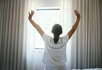 Image showing Stretching, curtains and back of woman at window for wake up, sunrise or good morning routine in bedroom at home. Awake, arms or get up from comfortable sleep to start bright new sunny day after rest