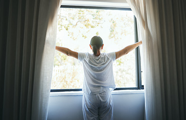 Image showing Open, curtains and back of woman at window for wake up, sunrise and good morning routine in bedroom at home. Awake, drapes and light of sunshine for inspiration, relaxing view or start bright new day