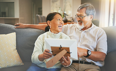Image showing Picture frame, happy and senior couple on a sofa bonding, talking and relaxing together in living room. Smile, laugh and elderly man and woman in retirement looking at photo memory in lounge at home.