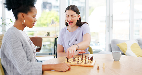 Image showing Girl friends playing chess in the living room for bonding, entertainment or having fun together. Happy, smile and young interracial women enjoying board game in the lounge of modern apartment.