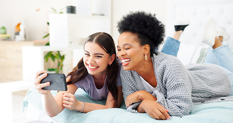 Image showing Happy, selfie and girl friends on a bed for bonding and relaxing together with a phone. Smile, technology and interracial female people taking a picture with cellphone in bedroom of modern apartment.