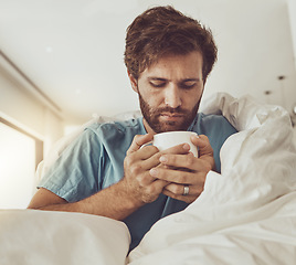 Image showing Tea, sick and a man with a blanket on a sofa in the living room of his home for recovery from cold or flu. Coffee, healthcare or lemon and ginger drink in a cup with a young person feeling unwell