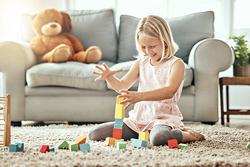 Image showing Kid, playing alone and toys on living room floor, house and educational game, fun and child development. Building blocks, girl and learning for creativity with activity, relax indoors and happiness
