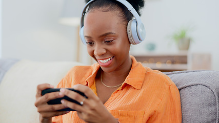 Image showing Phone games, headphones and woman in home on sofa for playing online gaming, podcast subscription or connection. Happy african person, video game or smartphone in living room for streaming multimedia