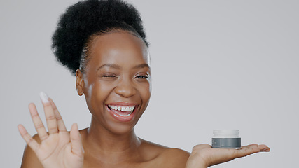 Image showing Woman, model and hand with cream for face, cosmetic and beauty aesthetic with wink for happiness. Black person, portrait and dermatology with smile for product, mockup and grey studio background