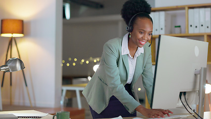 Image showing African woman, call center and typing in office with microphone, night or telemarketing with contact us. Consultant, crm and tech support agent with customer service, pc and reading at help desk