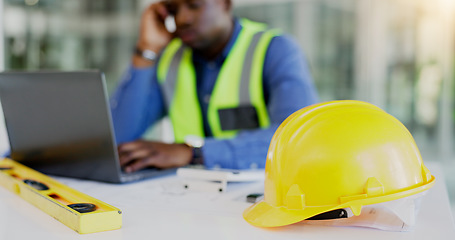 Image showing Engineering, construction tools and architect with helmet on desk with break from project, worksite or renovation. African, person or foreman with laptop to review of plans, building or real estate