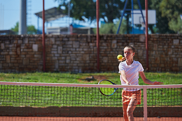 Image showing A young girl showing professional tennis skills in a competitive match on a sunny day, surrounded by the modern aesthetics of a tennis court.