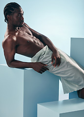 Image showing Body, relax and black man in studio for wellness, grooming or self care against a blue background. Topless, muscle and African male model posing with cosmetic care, treatment or fine art aesthetic