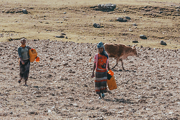 Image showing Ethiopian farmer woman walking with water canister