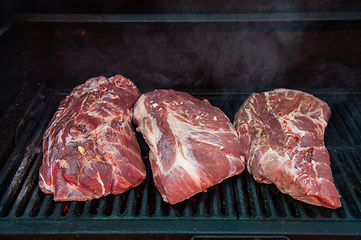 Image showing Beef steaks on the grill with flames