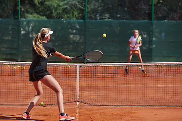 Image showing Young girls in a lively tennis match on a sunny day, demonstrating their skills and enthusiasm on a modern tennis court.