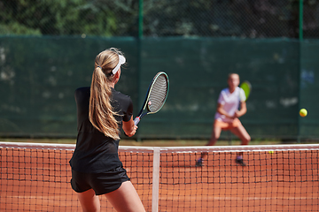 Image showing Young girls in a lively tennis match on a sunny day, demonstrating their skills and enthusiasm on a modern tennis court.