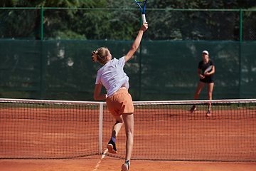 Image showing Young girls in a lively tennis match on a sunny day, demonstrating their skills and enthusiasm on a modern tennis court.