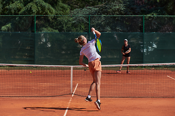 Image showing Young girls in a lively tennis match on a sunny day, demonstrating their skills and enthusiasm on a modern tennis court.